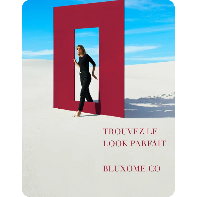 Dark-clad White woman walks through an abstract red door in the desert