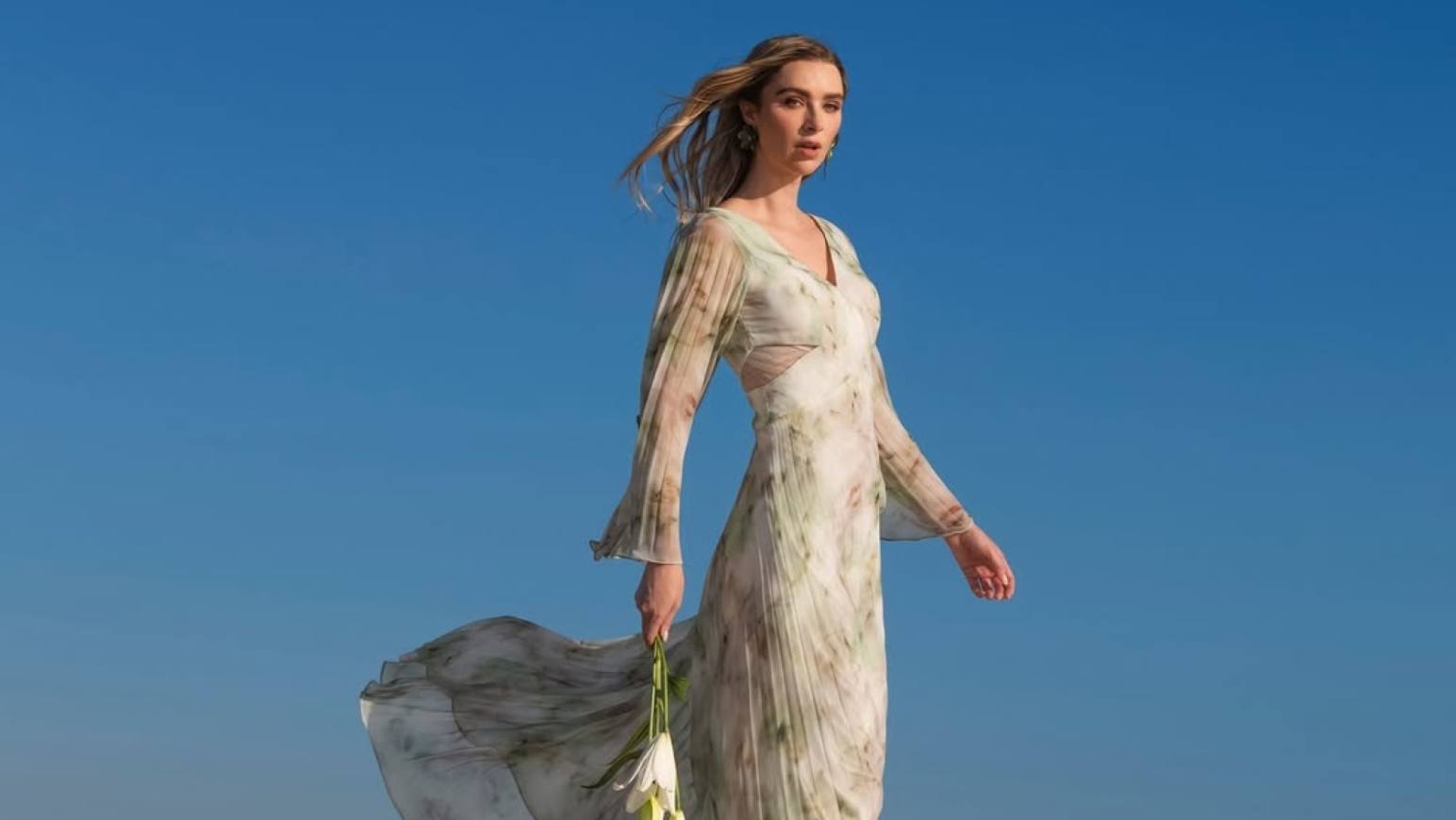 woman in floral dress outside with a blue sky