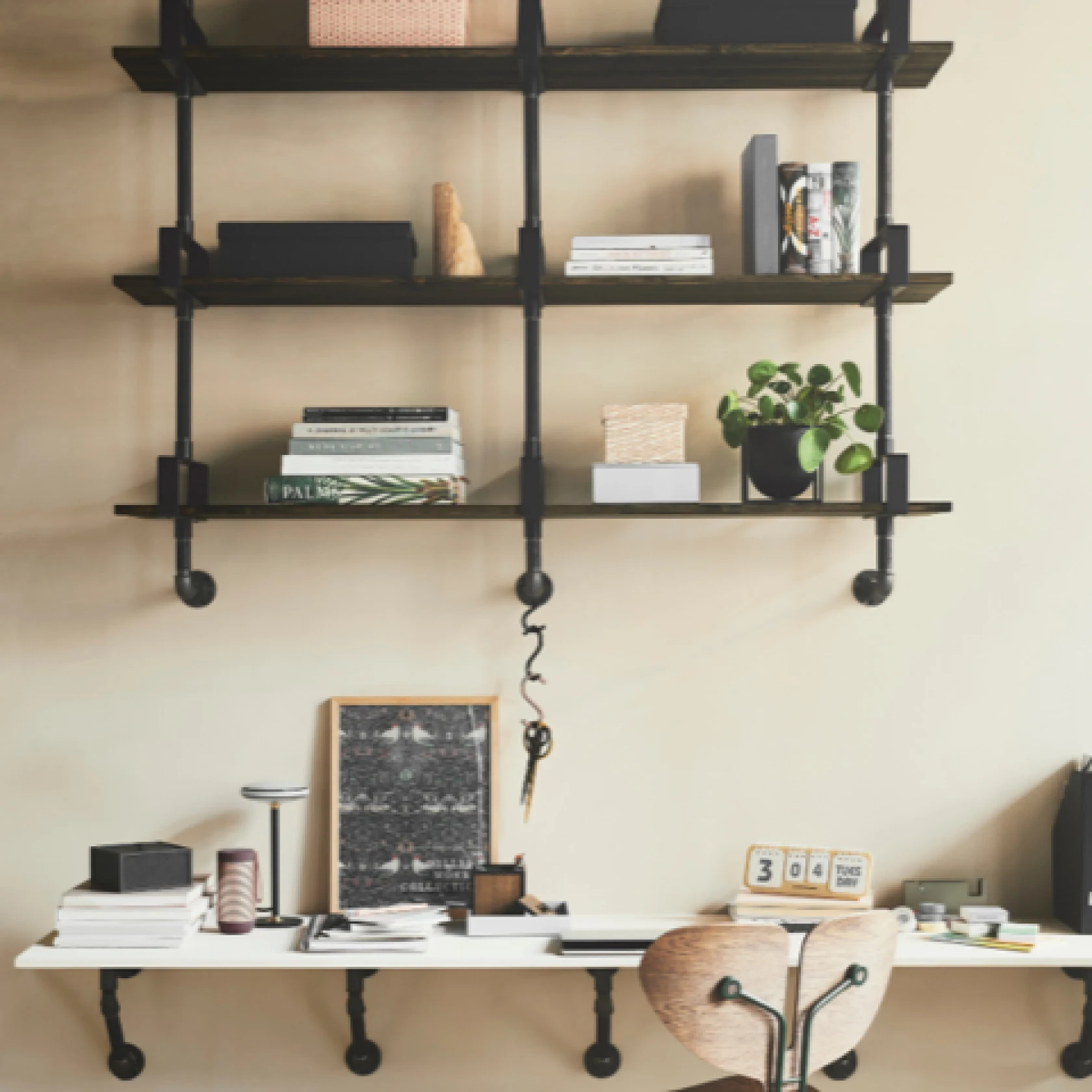 home office set up with industrial style bookshelf and built in desktop, styled with books and plants
