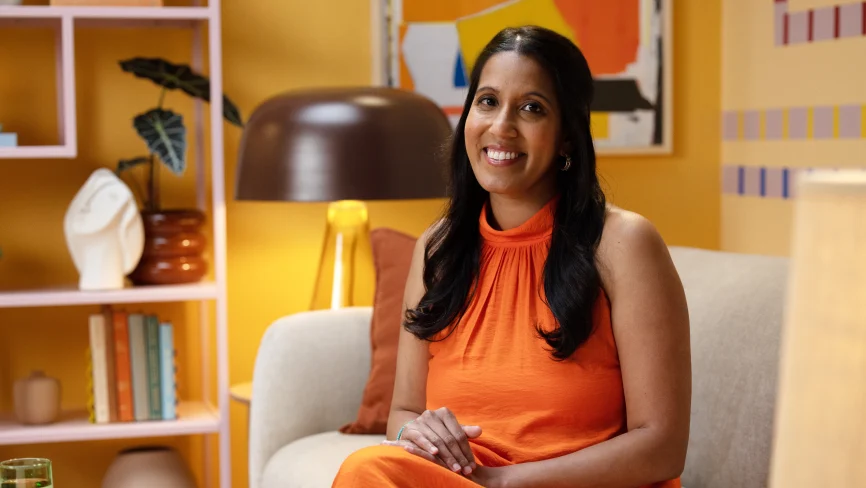 Preeti Farooque, líder de mensuração, posa para a câmera com um vestido laranja.