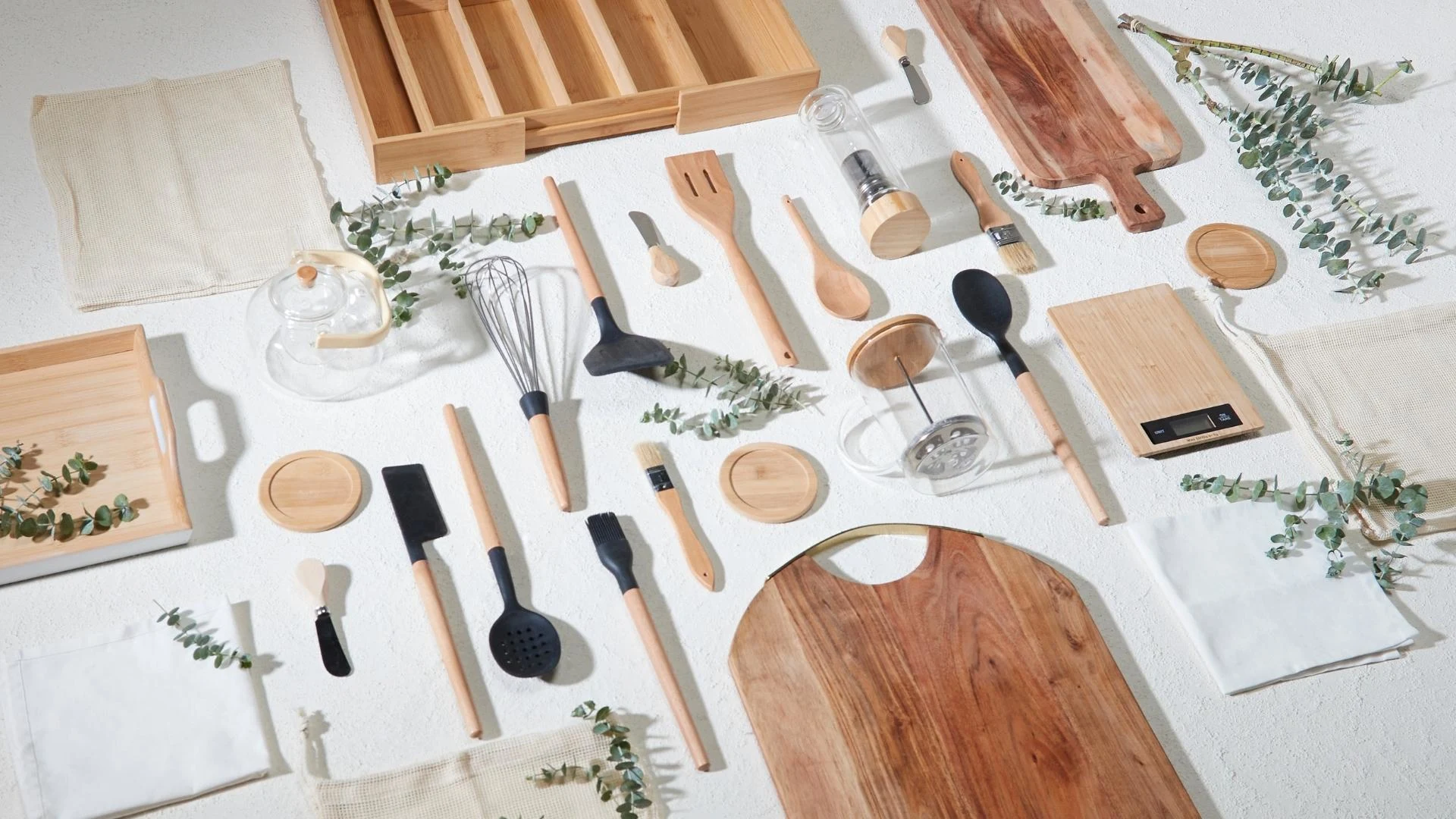 Kitchen cutlery and wooden accessories displayed on a table covered with a white tablecloth
