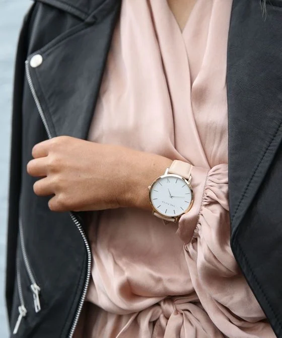 丸い文字盤の腕時計をつけてシルクのトップスを着た女性