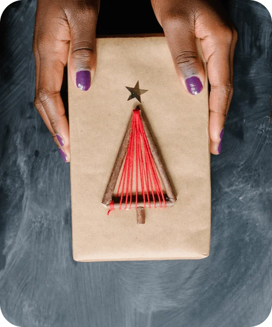 Black hands holding a gift wrapped in brown paper packaging