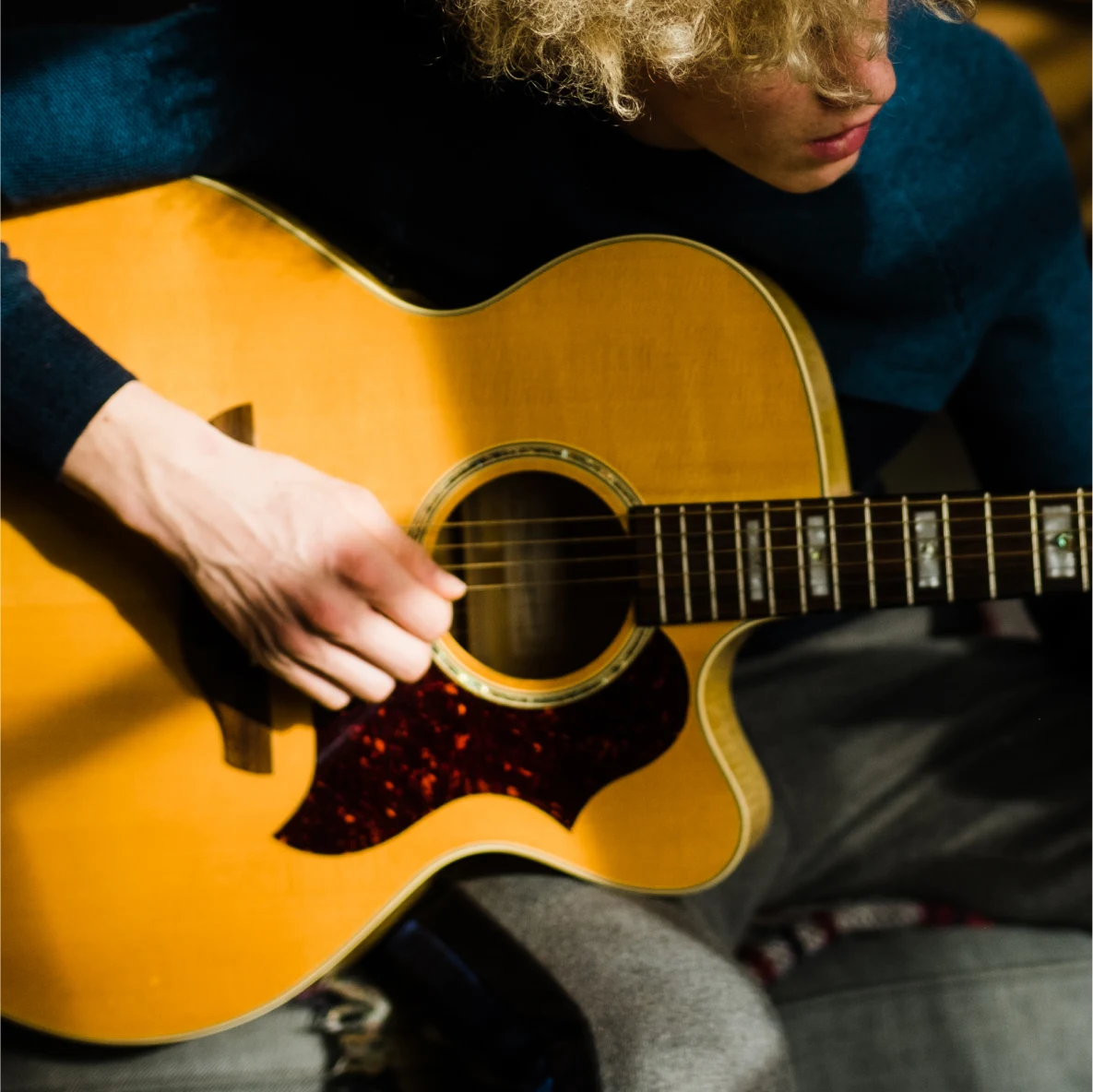 Man with blonde hair playing guitar