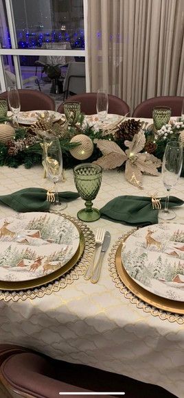 a dining table set with plates, glasses and flowers