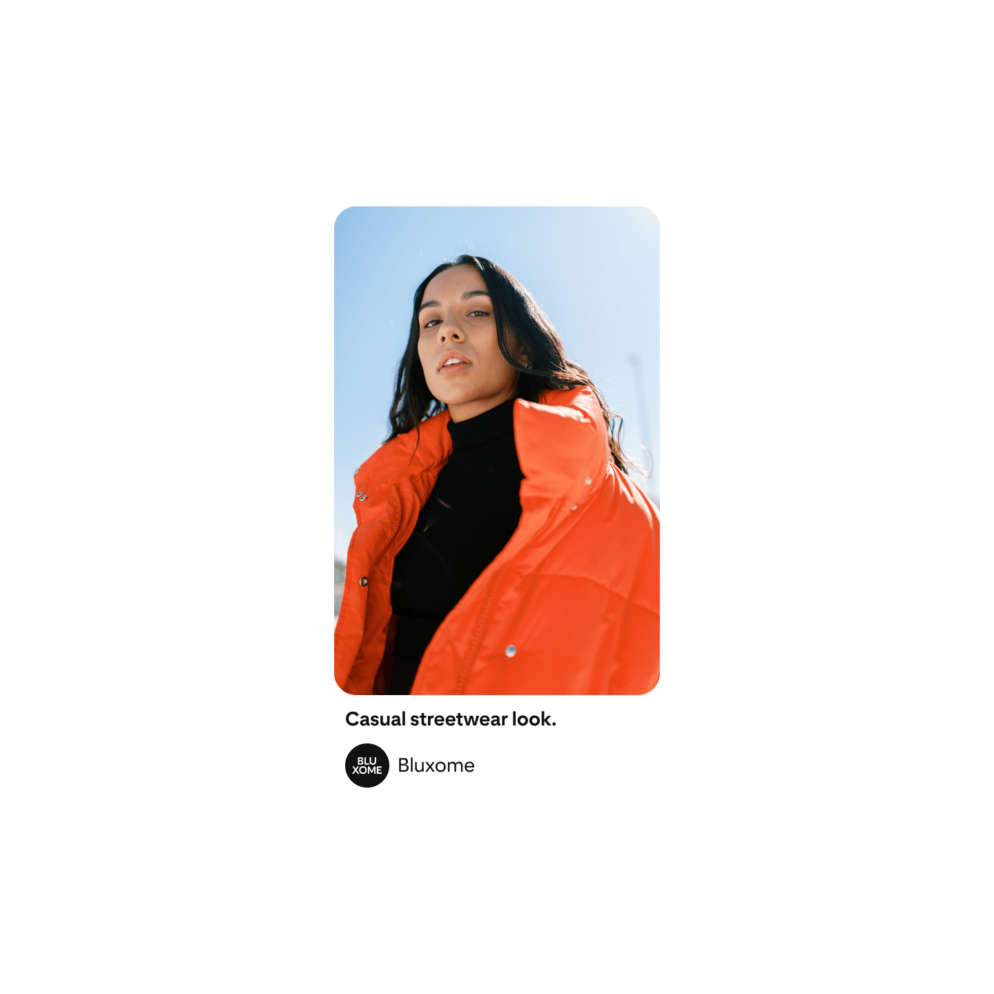 Woman with long, dark hair posed to camera in an orange puffer jacket and black turtle neck shirt.