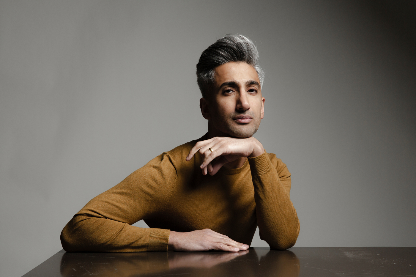 Head shot of Tan France against a tan background.