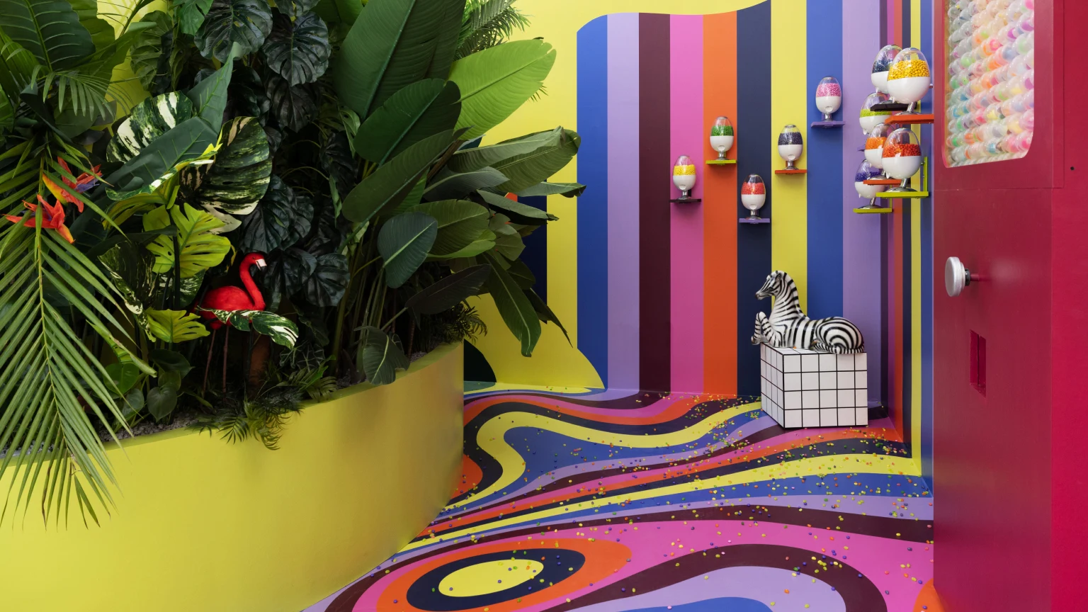  Conference space featuring tropical plants and a retro-patterned, brightly-colored floor design that continues up the walls.