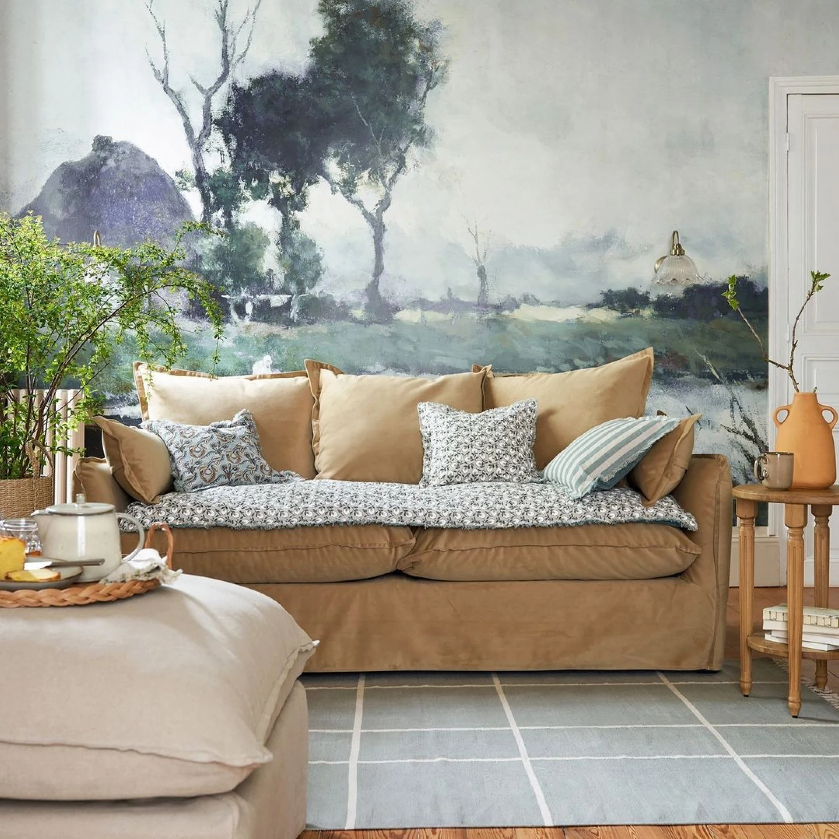 Canapé marron contre un mur peint, entouré d'un pouf moelleux, d'une table d'appoint en bois, de plantes d'intérieur et d'un tapis moderne