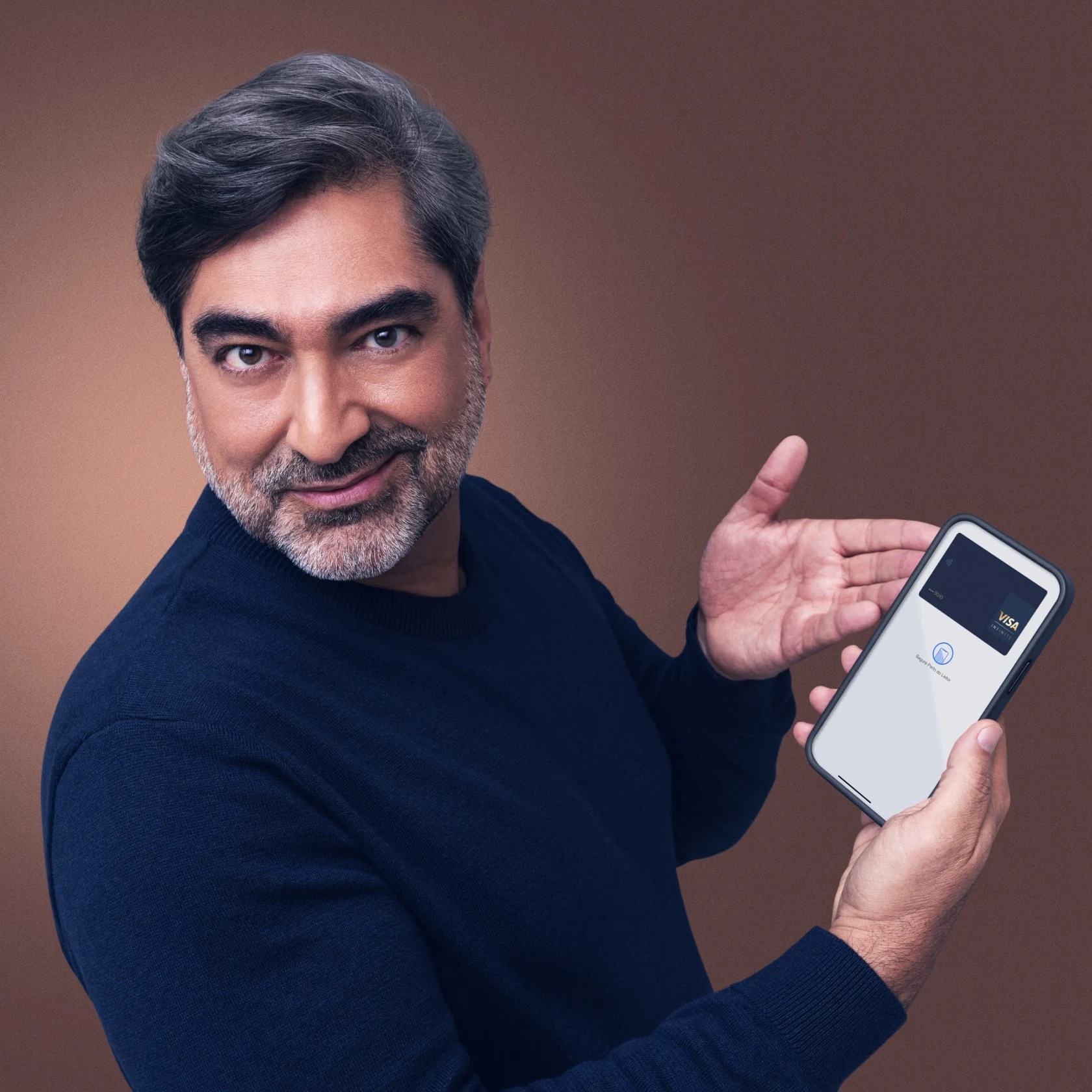 Homem sorrindo para a câmera segurando e exibindo o telefone mostrando o leitor de cartão Visa