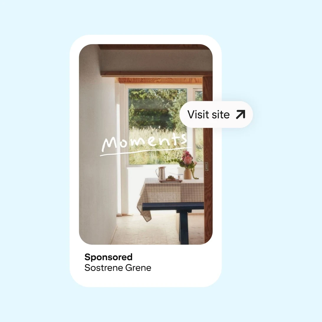 Mocked up Pinterest ad displaying a cozy indoor nook with a wooden table and bench by a window overlooking greenery. Text "Moments" and "Visit site" button featured. Sponsored by Sostrene Grene.