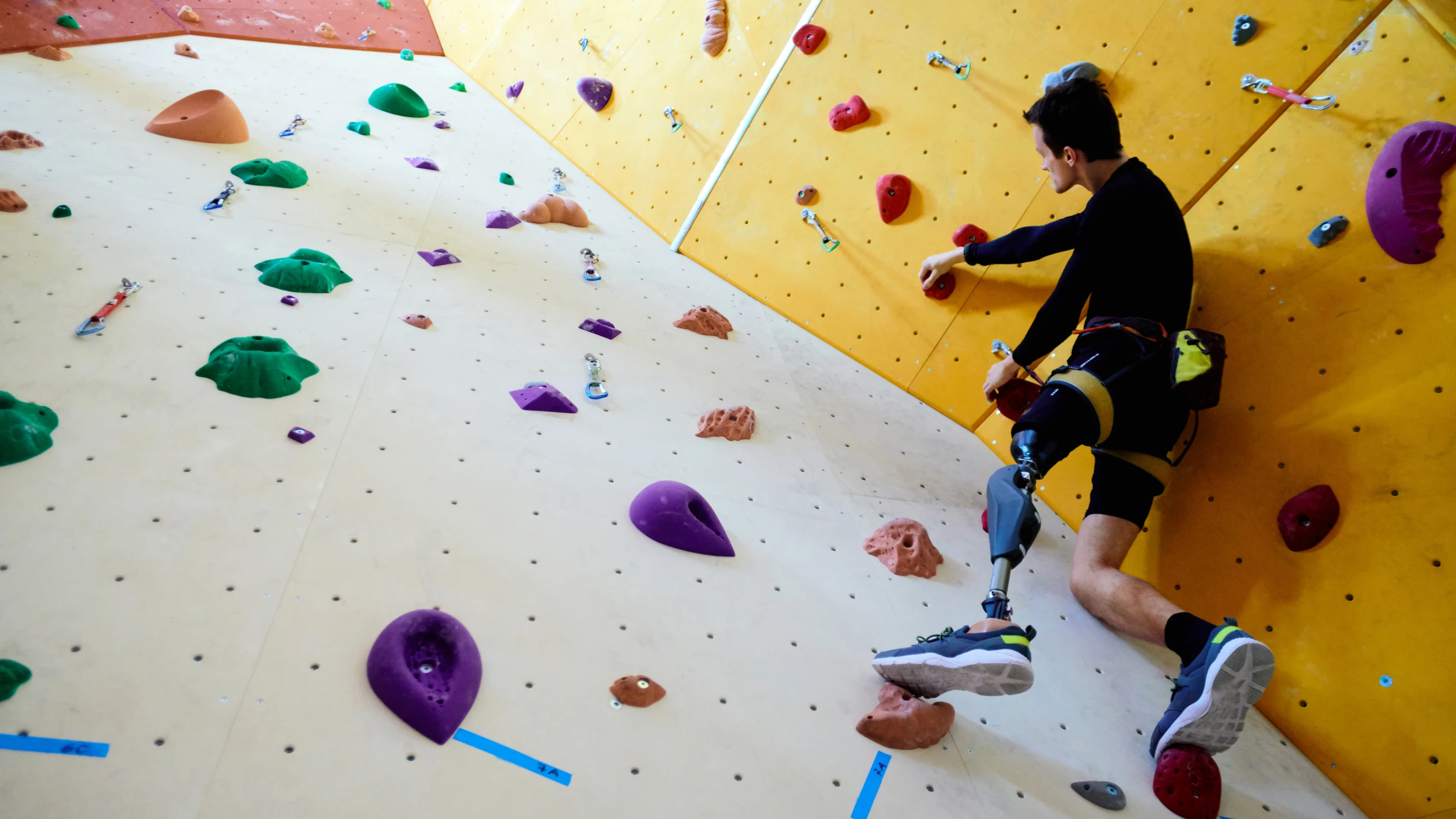 White man with a prosthetic left leg on a white, yellow and red climbing structure.