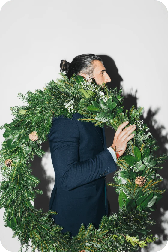 Homme blanc tenant une grande couronne de Noël