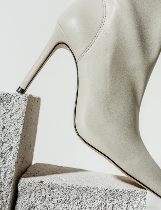 Taco de zapato stiletto de color blanco apoyado sobre un bloque de cemento
