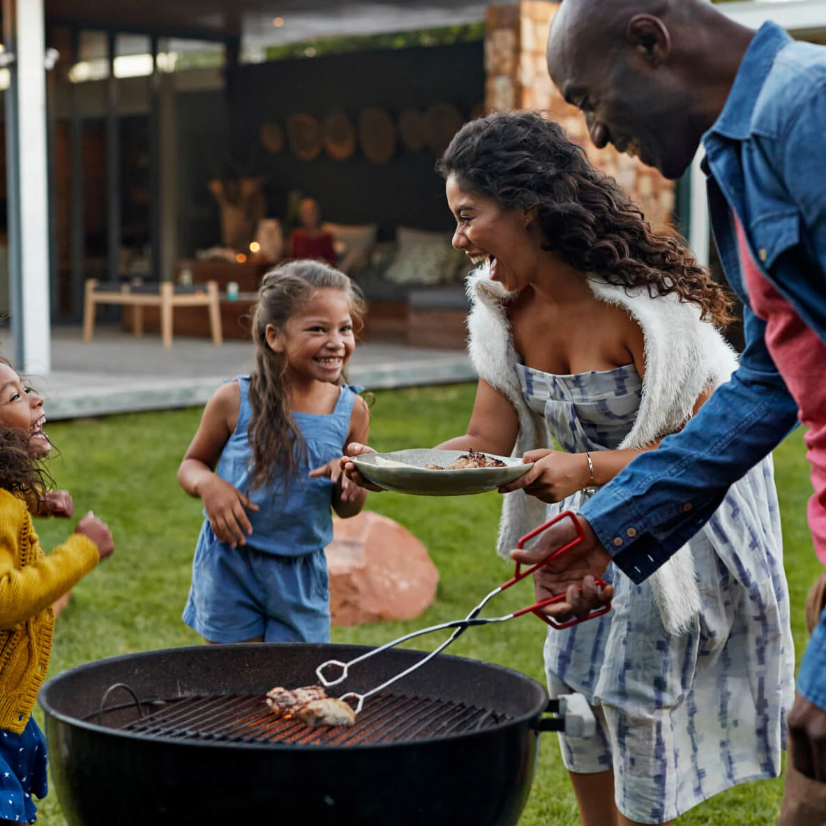 Young black family with two daughters enjoying a BBQ outside in the summertime.