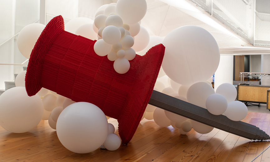 A gigantic red Pin replica among large white balloons in the Pinterest headquarters lobby
