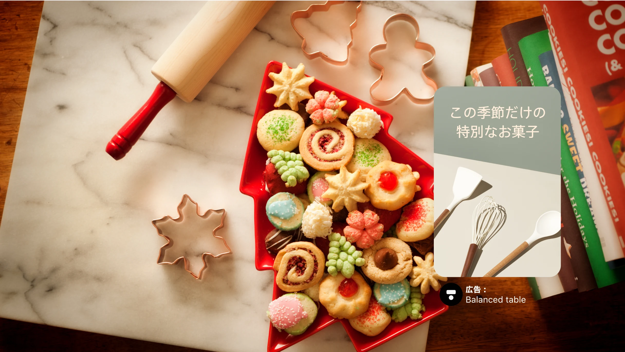 雪の結晶やツリーの形をしたクリスマスクッキーが入ったツリー型のトレイをメインにしたフル画面の画像、周りにはクッキー型とめん棒、右側にはお菓子作り用の本が積み重なっている。その上には「この季節だけの特別なお菓子」のテキストが入った広告ピン。