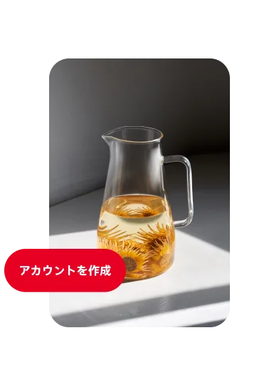 半分ほどまで水が入っていて中にオレンジ色の花が浸かっているガラスの水差しのピン、左側に「アカウントを作成する」ボタン付き。