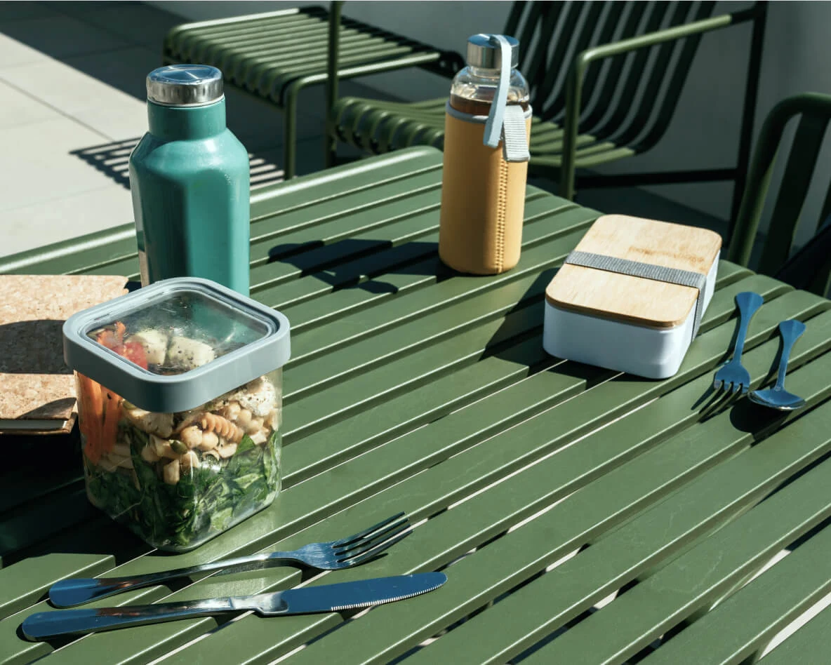 Reusable food containers and cutlery on a green outdoor table