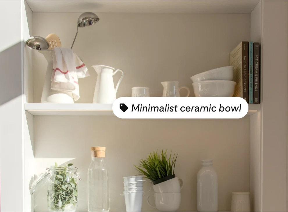 Two shelves with white vases and bowls and three books on the right side of the top shelf, with the product tag, minimalist ceramic bowl