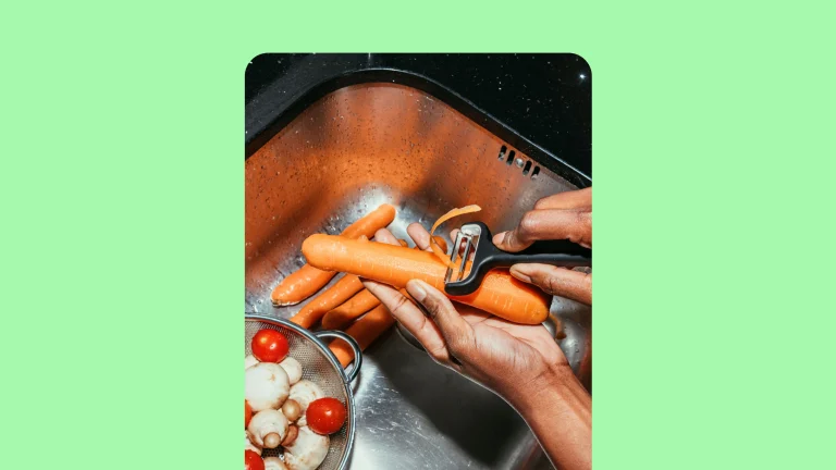 Idea Pin mostrando as mãos de uma pessoa negra descascando cenoura dentro da pia, com uma tigela com tomates e cogumelos, centralizado em uma imagem de fundo com folhas de manjericão.