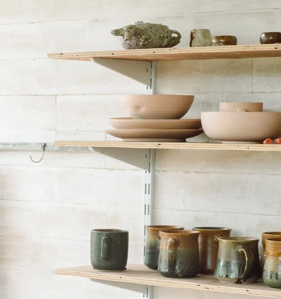 Cuencos de madera y tazas de cerámica en estanterías de madera