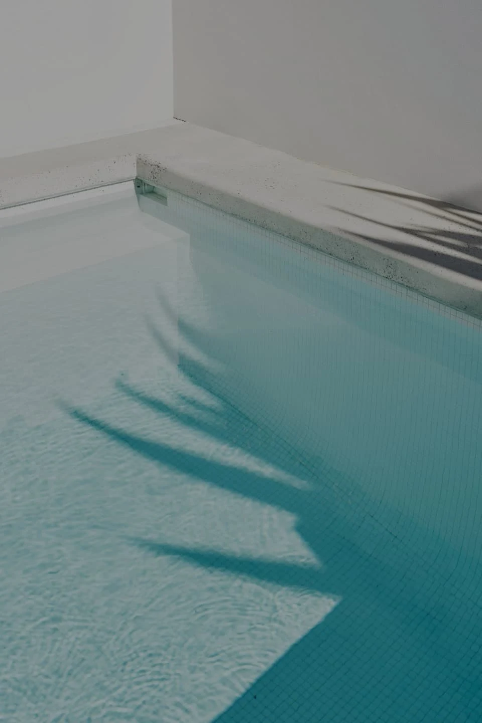 A still blue swimming pool with abstract shadow patterns