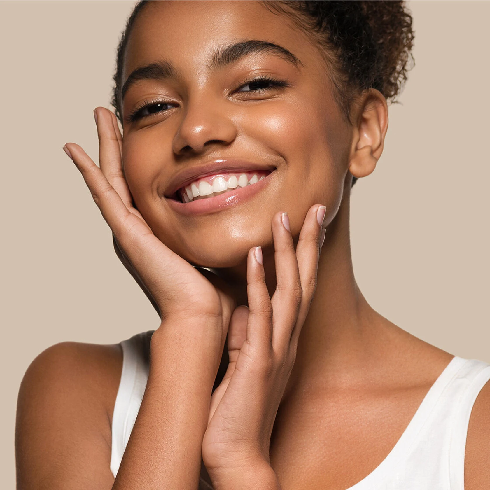 Woman with glowing skin holding her face with both hands