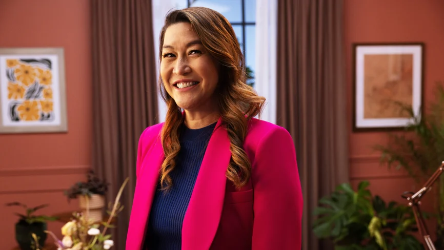 Sabrina Ellis, Chief Product Officer, trägt einen leuchtend pinken Blazer und ein blaues, hochgeschlossenes Oberteil und lächelt in die Kamera.