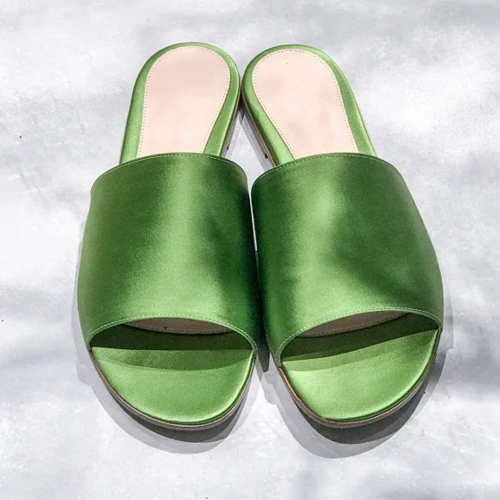 A pair of light green satin slip-on sandals.