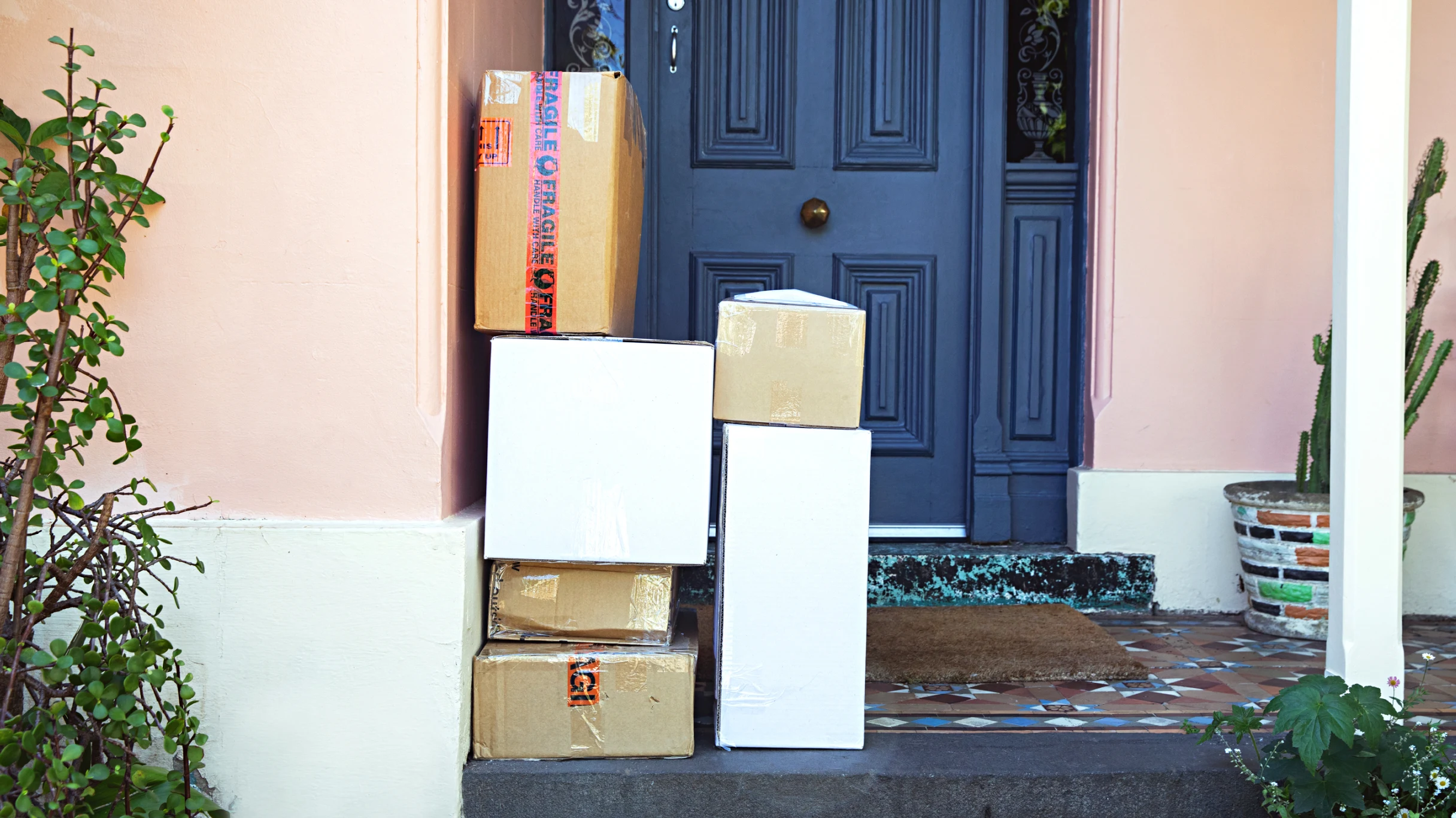 Six packages stacked on top of each other on the porch of a home. 