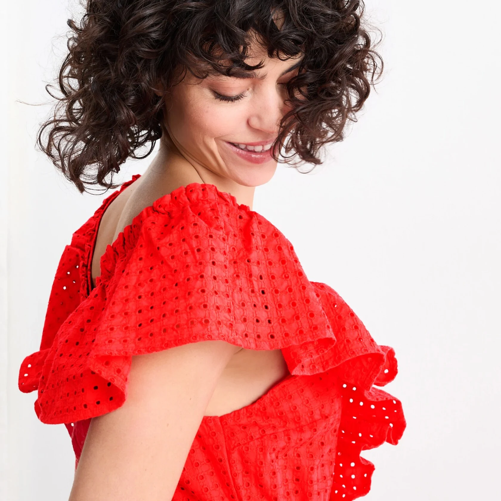 woman in red frilly dress looking down over her right shoulder