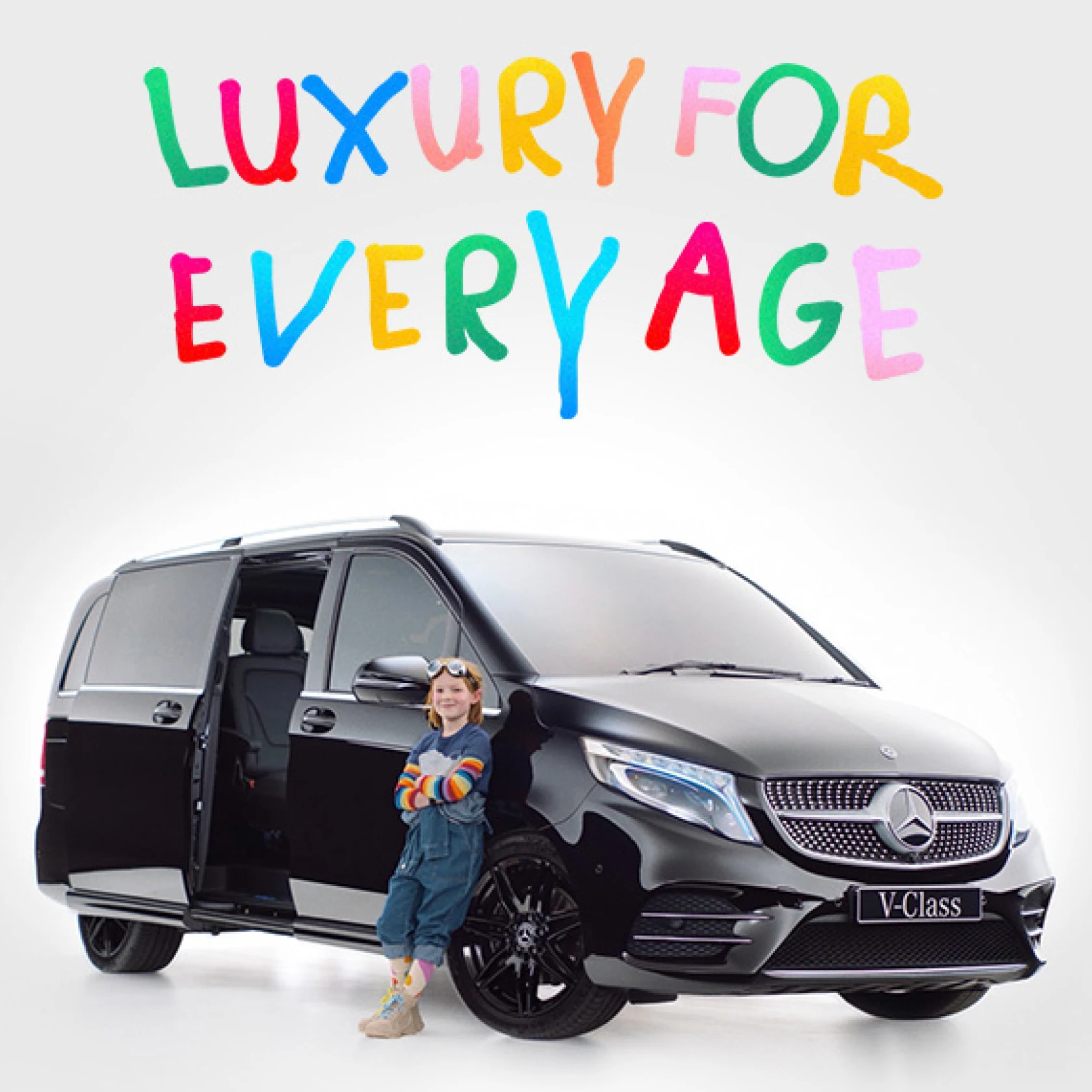 A child dressed in a colorful outfit leans against a Mercedes v-class with the text Luxury for Every Age written in a kid’s handwriting 
