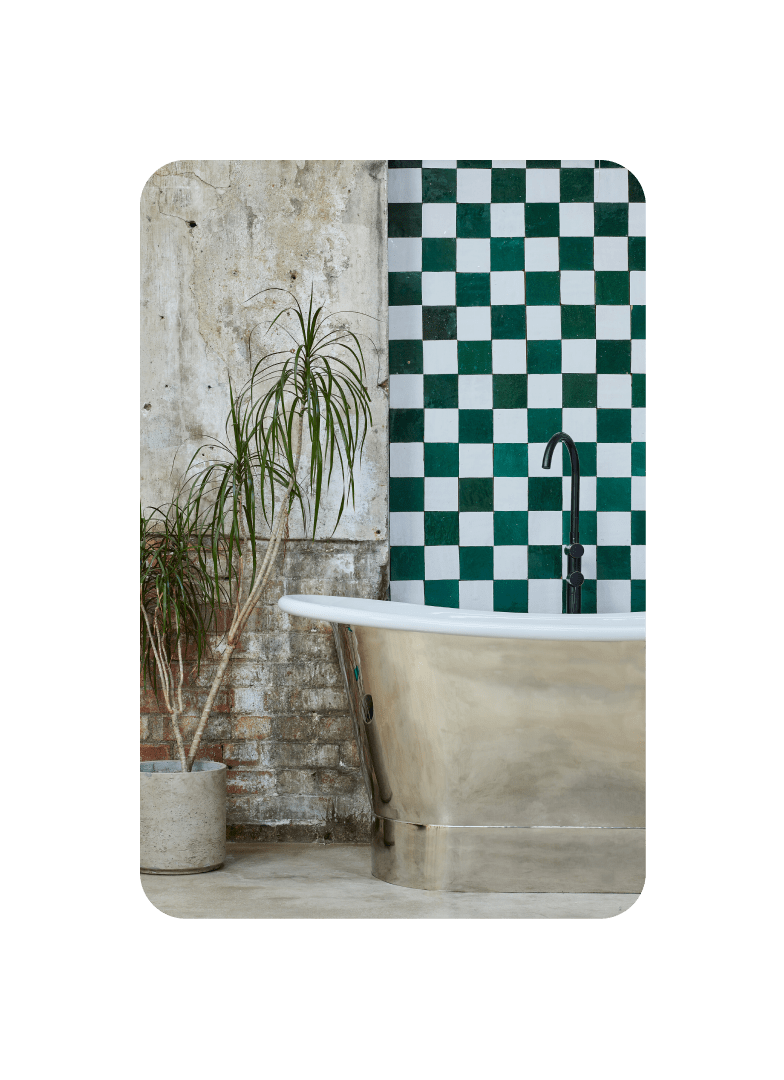 Pin von einem Badezimmer, in dem eine Palmenpflanze in einem Betontopf und eine metallische Badewanne vor einer Wand mit Schachbrettmuster steht.