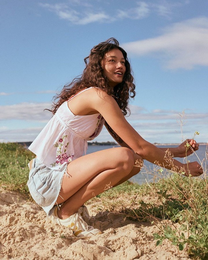 Model posing in the dunes wearing jeans shorts and a white top by Cotton On.