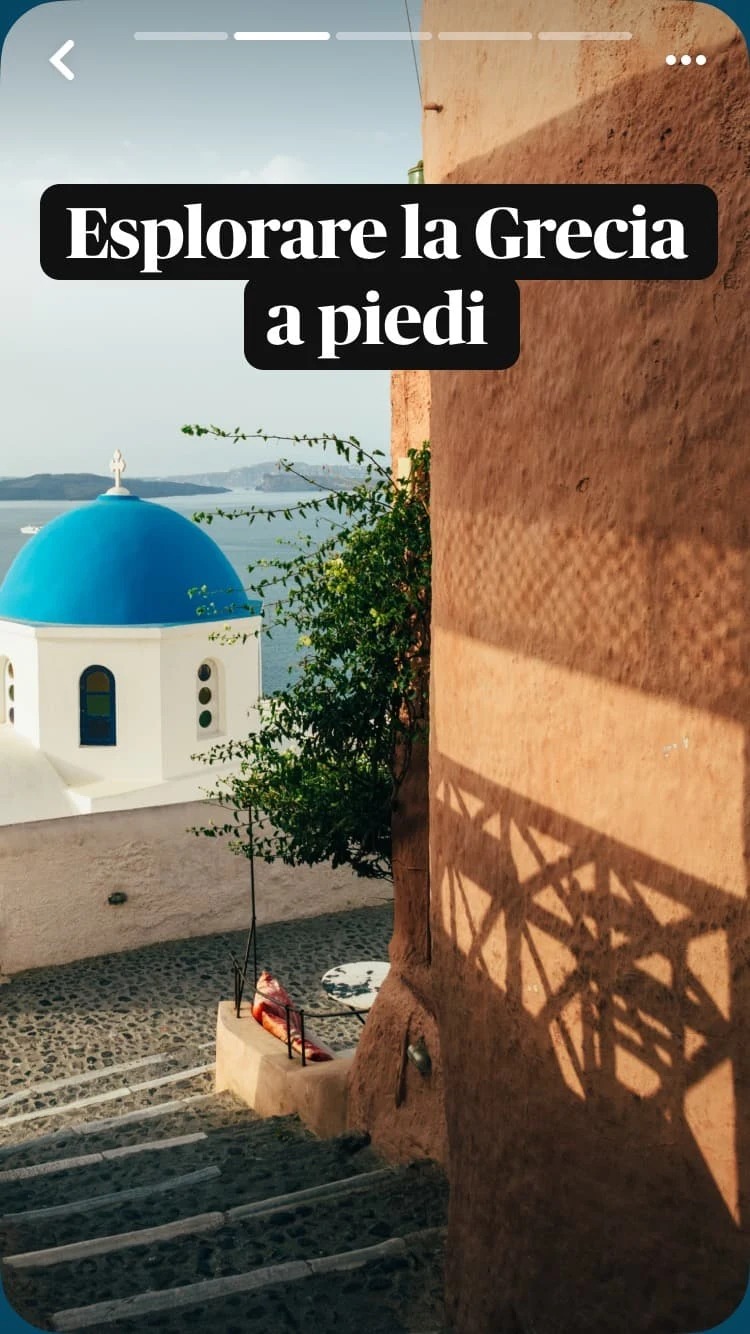 Una piccola scalinata a Santorini, in Grecia, conduce verso una chiesa con la cupola blu incorniciata dal mare. Una sovrapposizione di testo dice &quot;Esplorare la Grecia a piedi&quot;.