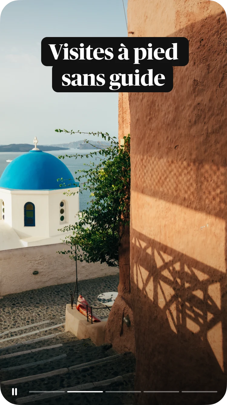 Marches en pierre menant à l'église au dôme bleu à Santorin, en Grèce, avec la mer pour toile de fond et un texte superposé : Visites à pied sans guide