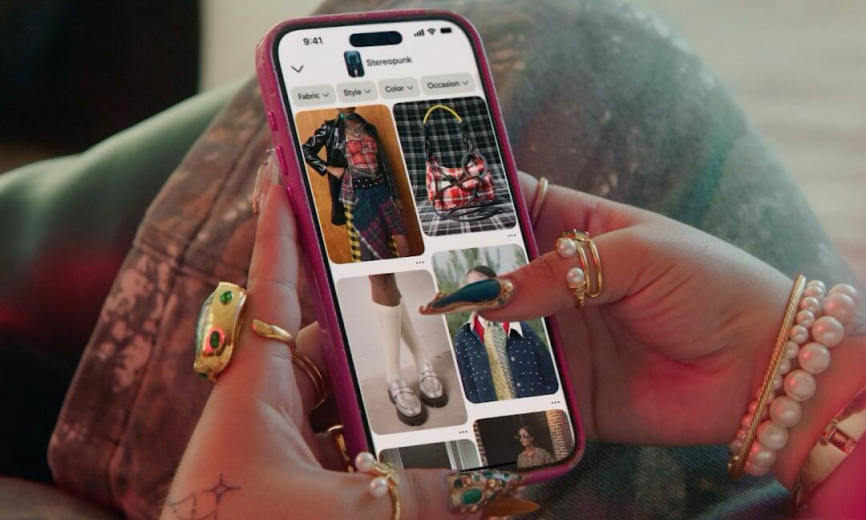 Close-up of a person’s hands scrolling Pinterest on a phone, with multiple rings, stacked bracelets, and highly decorated nails in focus.