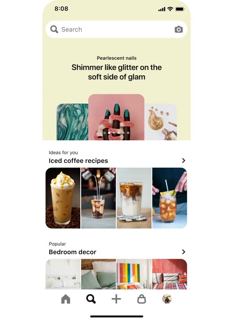 Mobile app search tab with a top-aligned search bar with 3 stacked nail idea pins titled “Pearlescent nails: Shimmer like glitter on the soft side of glam”. Below, a section titled “Ideas for you: Iced Coffee Recipes” with 4 pins and another section titled “Popular: Bedroom decor” with 4 pins.