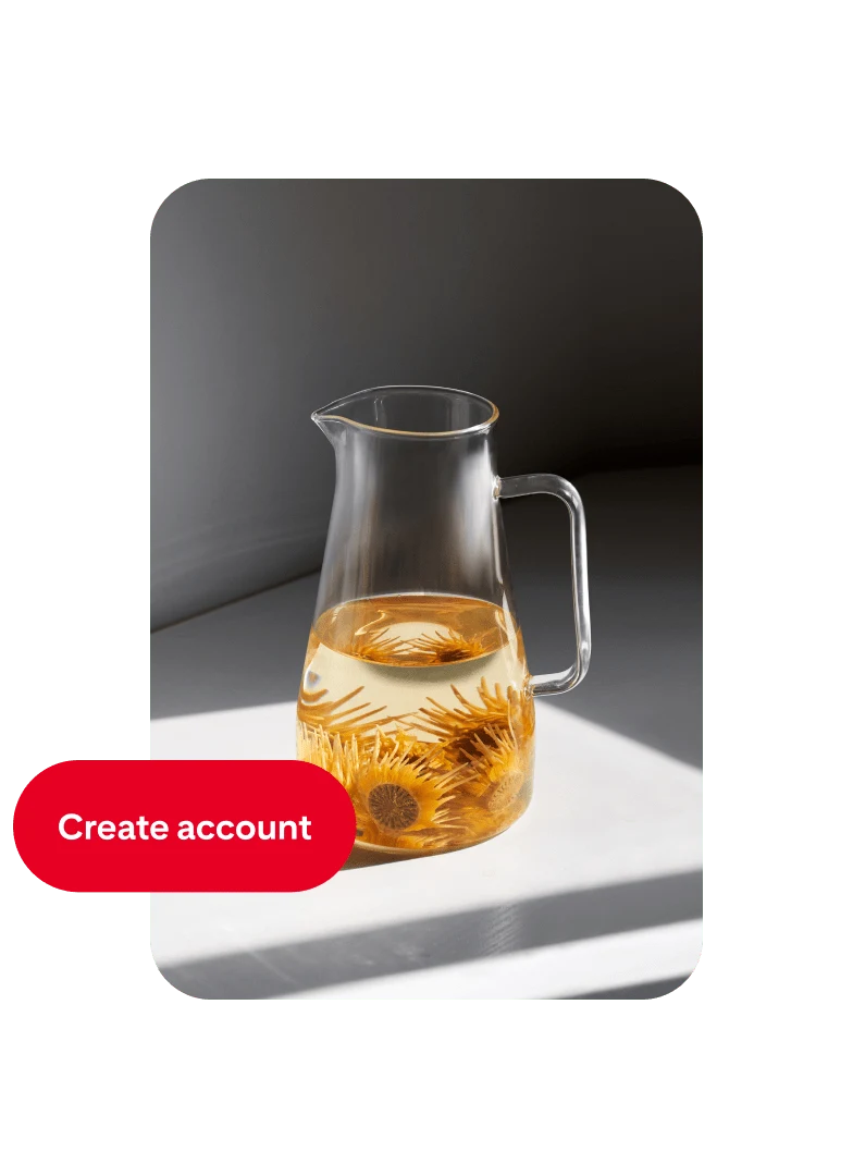 Pin so skleneným džbánom spolovice naplneným vodou a pomarančovými kvetmi s tlačidlom „Create account“ vľavo.