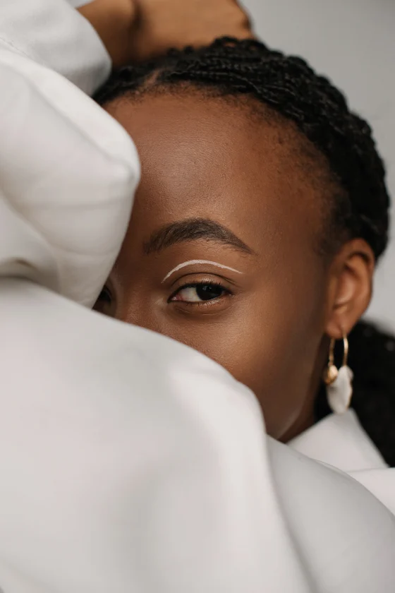 A Black woman dressed in white peeks over shoulder