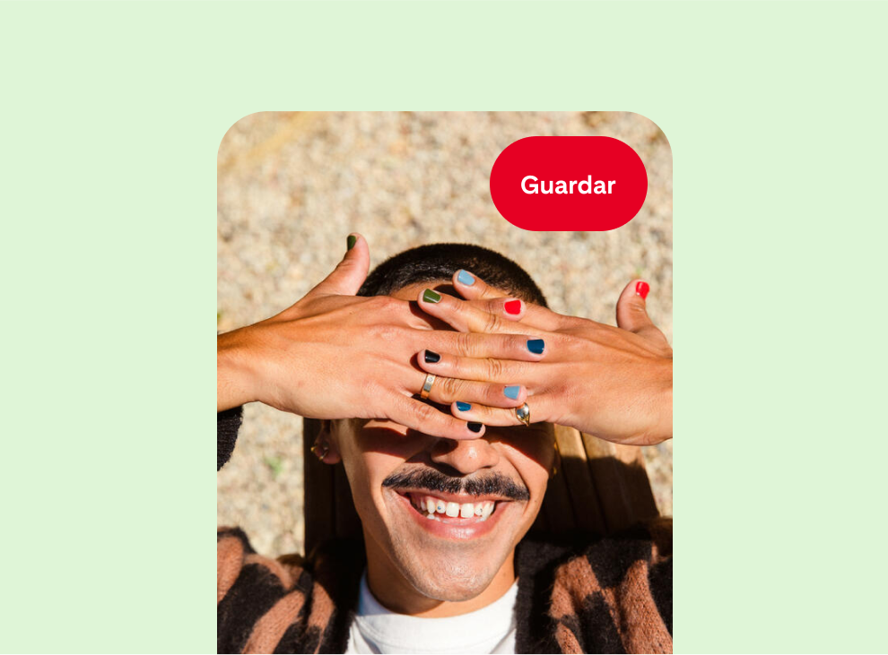 Una persona blanca sonríe mientras se cubre los ojos del sol. Cada dedo tiene un color de esmalte de uñas diferente.