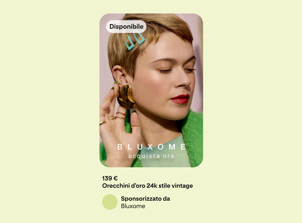 Pubblicità su sfondo verde che mostra una donna con indosso una giacca verde mentre tocca delicatamente con la mano l'orecchino che porta.