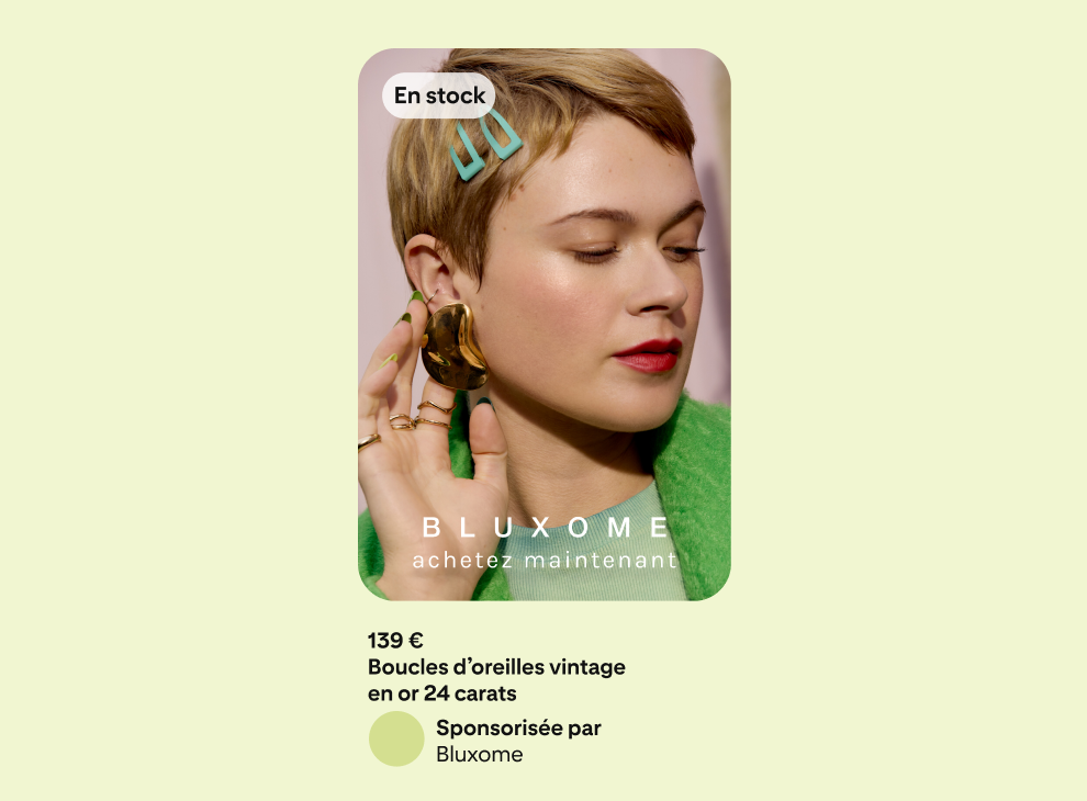 Une publicité sur un fond vert montrant une femme vêtue d’une veste verte et touchant une boucle d’oreille qu’elle porte du bout de ses doigts.