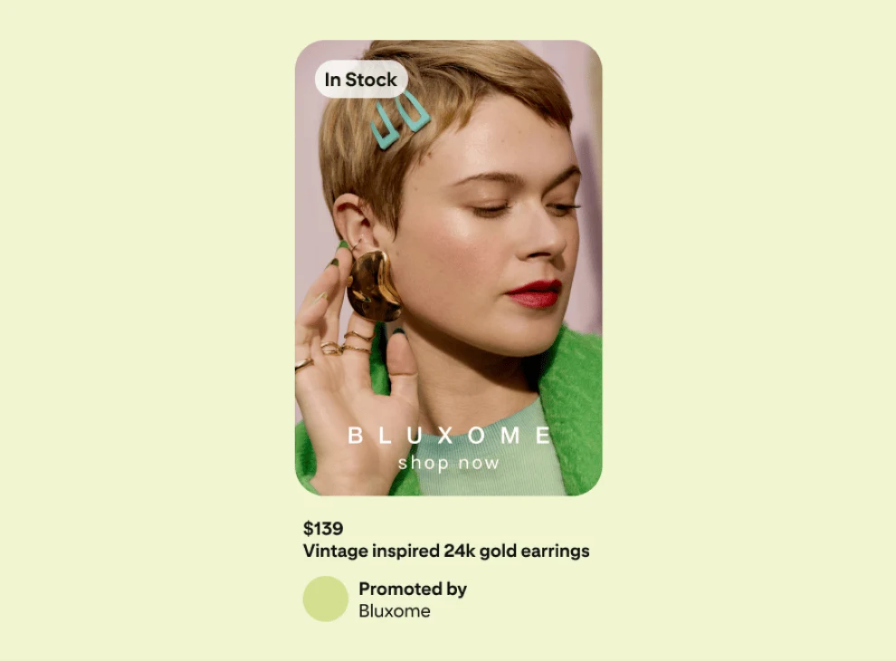 Advertisement on a green background showing a woman in a green jacket, delicately holding an earring she is wearing.