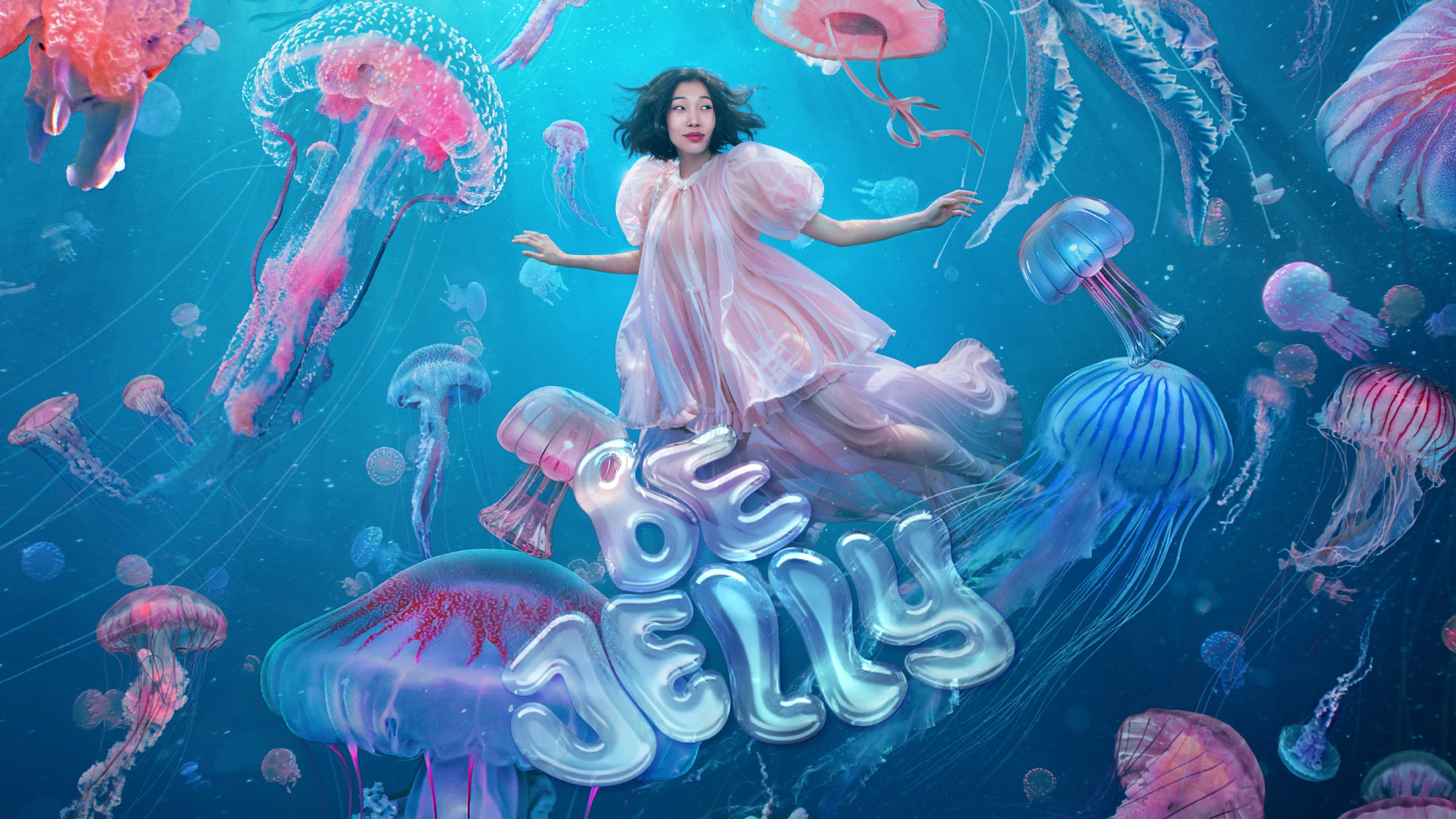 Whimsical image of an Asian woman wearing a sheer pink dress swimming amidst multicolored jellyfish in the sea. “Be Jelly” is written out in jelly-like bubble font in the center of the image.