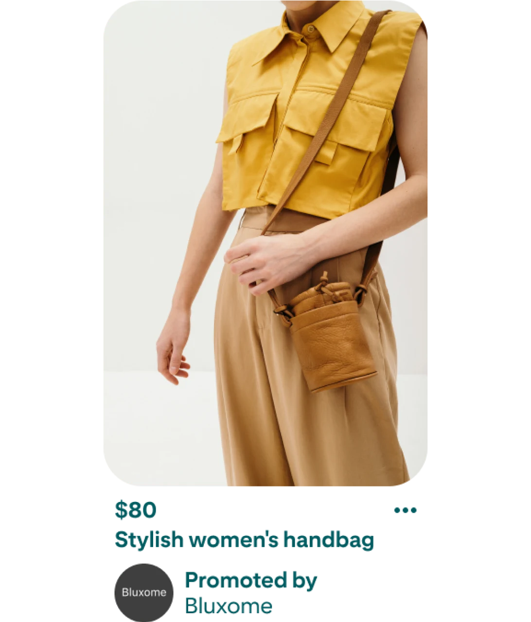 Kép egy női táskát eladásra kínáló pinről. A pinen egy barna táskát viselő személy látható. A táska hosszú pánttal rendelkezik, amely a személy vállára van akasztva. A képen látható személy egy galléros, ujj nélküli, sárga inget visel, felülről lefelé szűkülő, khaki színű nadrággal. A személyről készült kép alatt a táska ára és leírása látható. A feltüntetett ár 80 dollár, és a leírás így szól: „Stílusos női táska, hirdető: Bluxome”. 