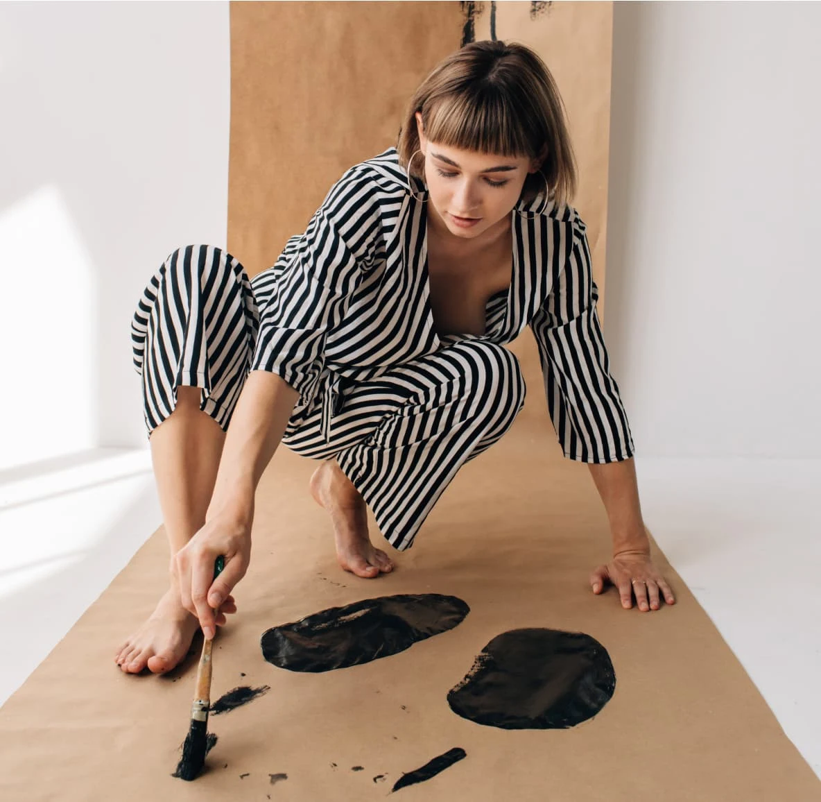 Person painting black dots in a kraft paper