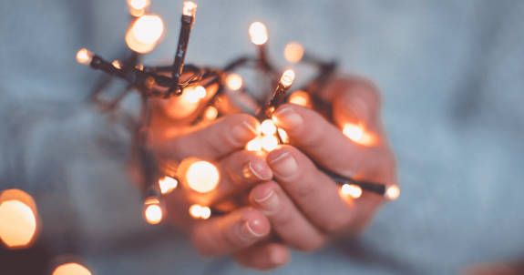 Close-up of hands holding a bundle of white Christmas lights.