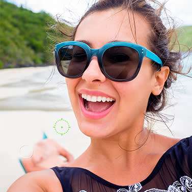 Close up of smiling woman at beach with sunglasses. Old man in background being erased by PicMonkey's Clone tool.